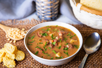 Peas soup with meat, smoked sausage and croutons. Selective focus, close-up.