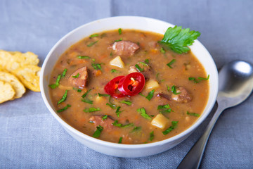 Peas soup with meat, smoked sausage and croutons. Selective focus, close-up.