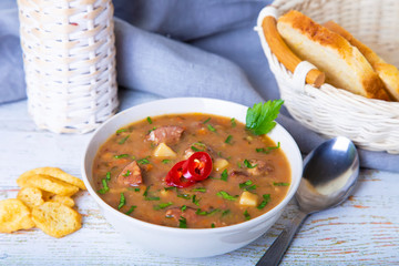 Peas soup with meat, smoked sausage and croutons. Selective focus, close-up.