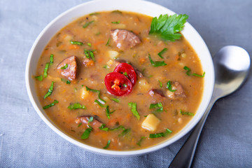 Peas soup with meat, smoked sausage and croutons. Selective focus, close-up.