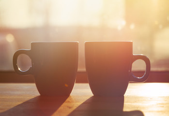 two cups of coffee on wooden table in morning sunlight