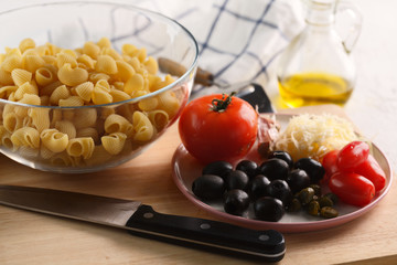 cooking pasta. Ingredients: tomatoes, Parmesan, olives and pasta.