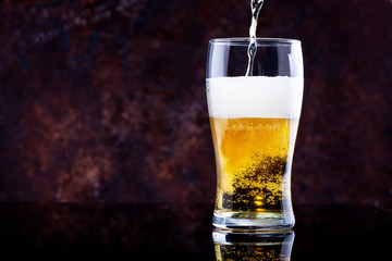 glass of beer with foam on a dark background