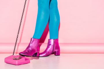 cropped view of young woman in blue tights near retro phone on pink
