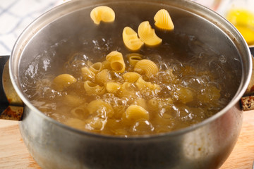 cooking pasta. Pasta falls into boiling water in a metal pan.