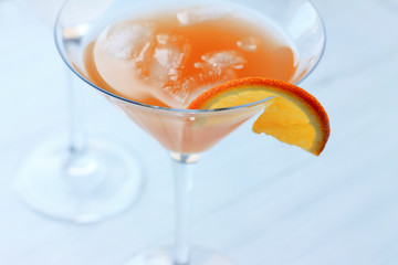 cocktail with ice in a glass on the edge of a glass of orange light background top view