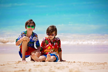 Happy beautiful fashion family, mom and children, dressed in hawaiian shirts, playing together on the beach
