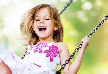 Little child blond girl having fun on a swing