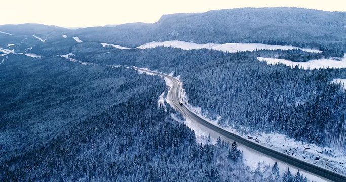 A truck pass on a highway in a Canadian national park. There are vast coniferous forests.