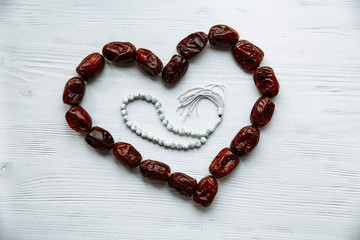 heart shaped by dates and white rosary for Ramadan and Friday message concept.