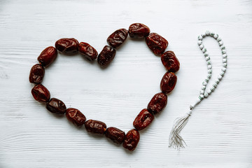 heart shaped by dates and white rosary for Ramadan and Friday message concept.