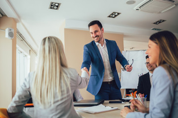 Business people shaking hands in meeting room. Selective focus.