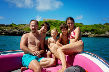 Obraz premium Happy beautiful fashion family, children and parents, dressed in hawaiian shirts, enjoying day trip with speed boat