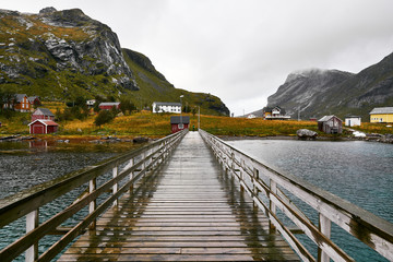 Wooden bridge on the water leading to the village Vinstad and Bunes Beach in moskenesoya on Lofoten Islands in Norway. The village consists of several traditional cabins in the mountains.