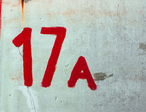 Nuber Seventeen A Drawn By Red paint On Whitewashed Wall. Shabby Facade of Fence With Damaged Сrack Plaster