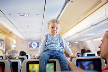 Father, entertaining little toddler boy on board of aircraft on a long distance international flight
