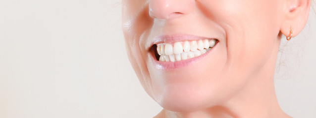 Mature woman showing perfect natural white teeth on the side