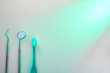 Dentistry tools on white table illuminated with green light top