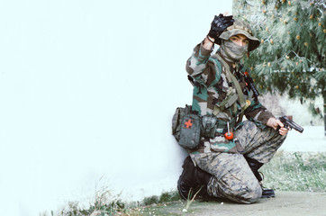Special forces soldier holding rifle gun take cover behind a wall Hand signal