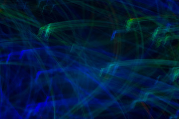 Blurred neon lights in motion. Thin blue and green lines on dark background. Lens flare effect.