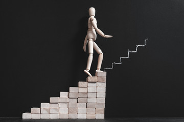 Career aspiration. Wooden man climbing stairs. You can do it. Drawn in chalk steps ahead. Articulated manikin composition.