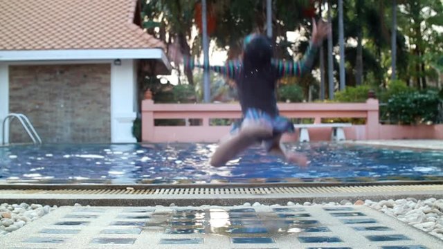 Asian smile child girl jumping in tropical blue swimming pool in summer