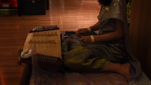 Close-up of Thai or chinese musician playing a traditional zither khim musical instrument