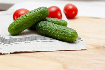 Fresh red tomatoes and cucumbers lie on towel