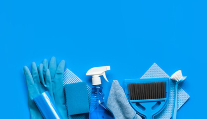 Blue set for spring cleaning in the house - rags, a bottle of cleaning agent, rubber gloves, sponges, brushes and a scoop with a broom. Top view. Place for text.