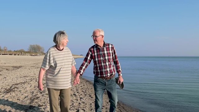  fr&ouml;hliches, gl&uuml;ckliches, verliebtes Rentner Ehepaar, Senioren gehen am Strand spazieren. Alte Frau, alter Mann