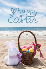 Easter bunny with basket and color eggs on the ocean beach