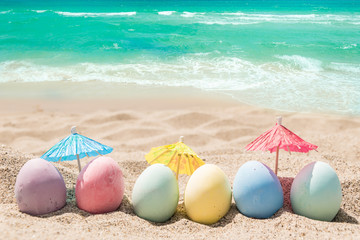 Fototapeta na wymiar Happy easter lettering background with eggs on the sandy beach