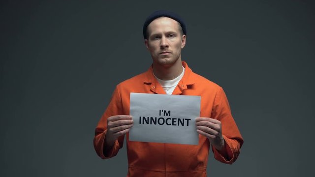 European imprisoned male holding I am innocent sign in cell, asking for justice