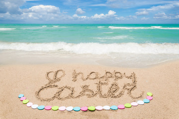 Fototapeta na wymiar Happy easter lettering background with eggs on the sandy beach
