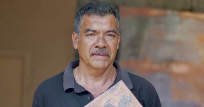 Portrait of a serious looking hispanic man holding a piece of copper