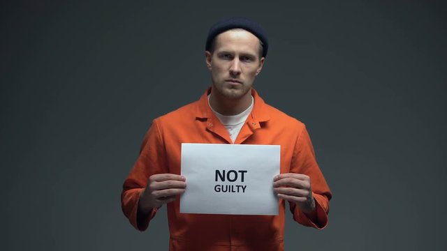 Caucasian prisoner holding Not guilty sign, asking for justice, human rights