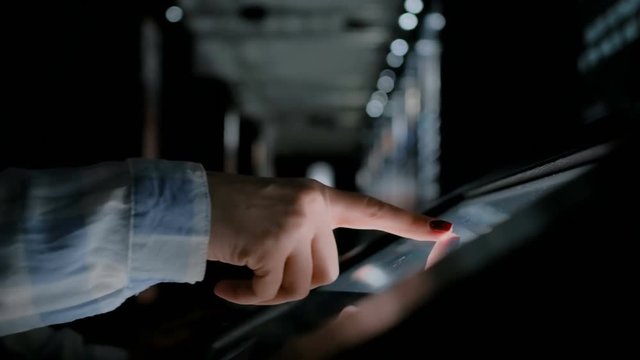 Education and technology concept - woman using interactive touchscreen display of electronic kiosk at modern history museum with low light illumination - close up shot