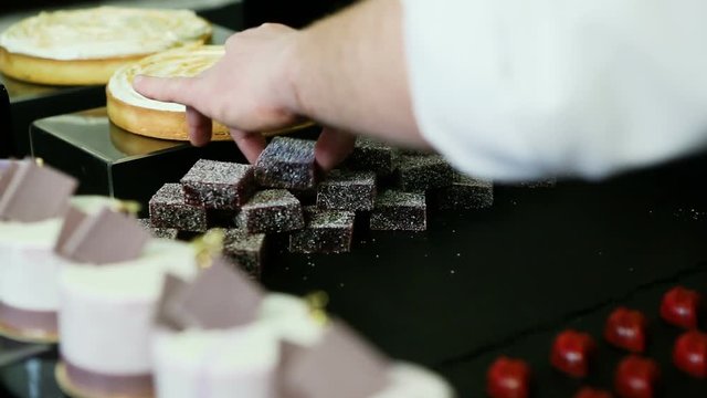 confectioner hands put handmade barry marshmallows in big pyramid at assorted candy bar table