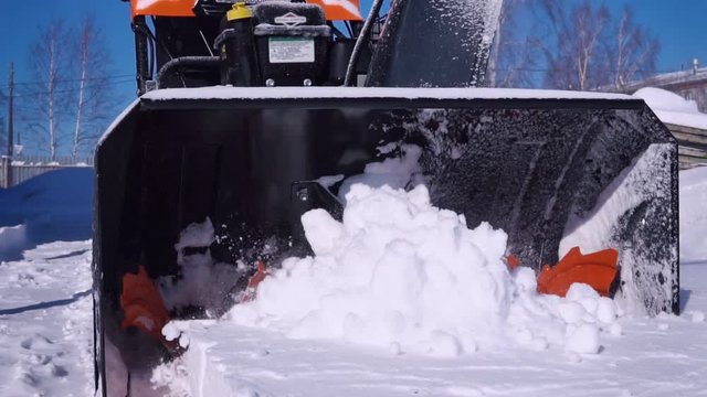 A man cleans the snow with a snowblower during a snowfall. Slow motion.