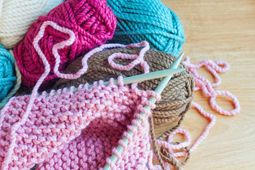 Skeins of thread and knitting needles on wooden background.