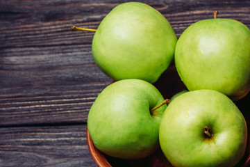 Beautiful ripe apples green in a bowl on a wooden table top view