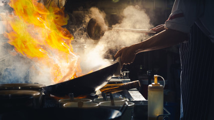 Chef stir fry in wok - obrazy, fototapety, plakaty