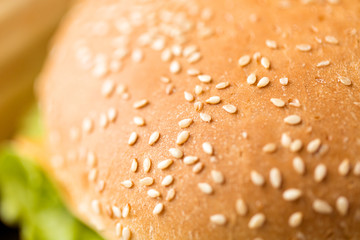 fast food and unhealthy eating concept - close up of hamburger bun crust with sesame seeds