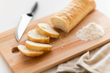 food, junk-food and unhealthy eating concept - close up of white ciabatta bread on wooden cutting board, knife and kitchen towel