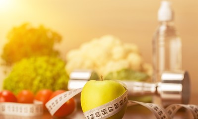 Dumbbell with bottled water , measuring tape and food isolated on white background