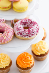 fast food, dessert and sweets concept - close up of glazed donuts and cupcakes on stand