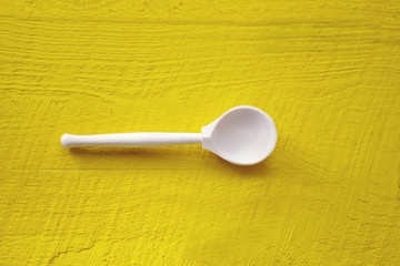empty wooden spoon on a yellow wooden background