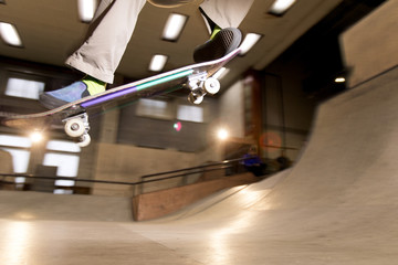 Action shot of unrecognizable young man doing skating trick flying in air at skateboard park, shot with flash