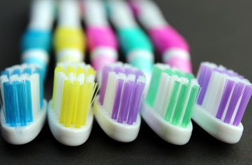 Multi-colored toothbrushes lie on a black background