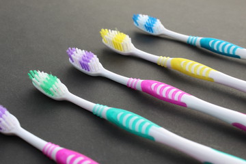 Multi-colored toothbrushes lie on a black background